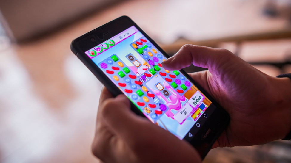 an image of a gamer playing Candy Crush with a smartphone.