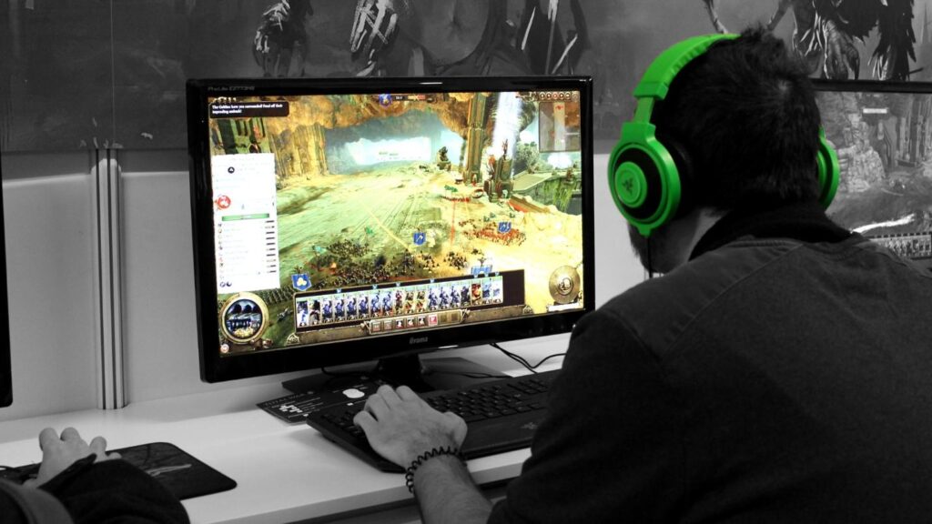 an image of a man with a green headset playing with his pc