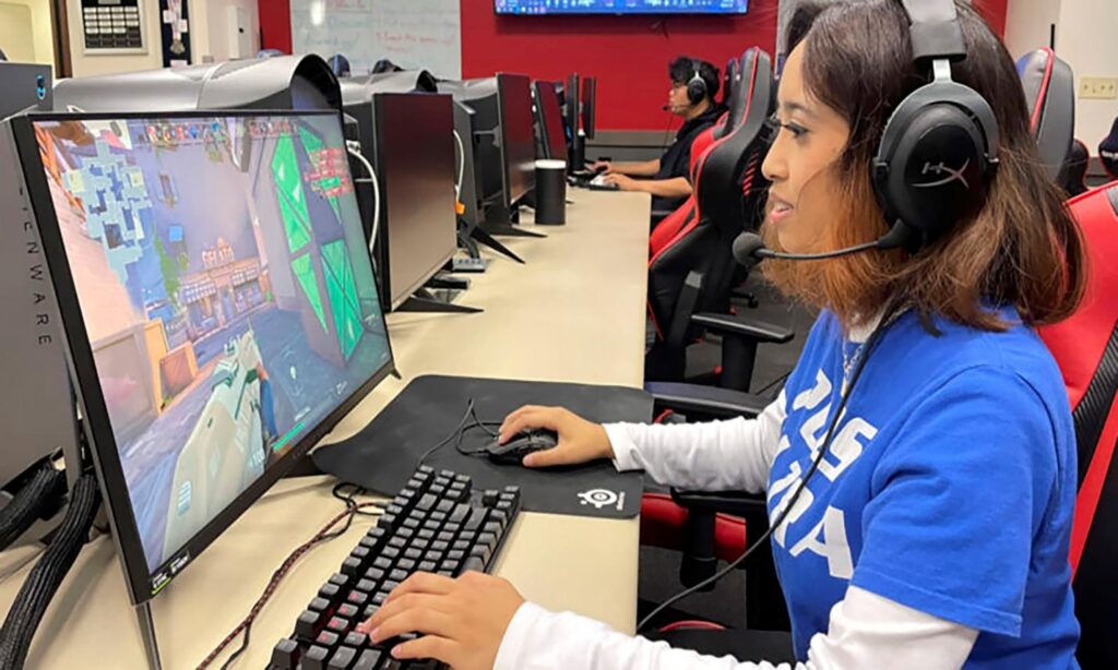 an image of a player behind her gaming computer while playing an Online FPS